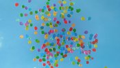 multiple coloured balloons flying in blue sky