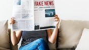 woman reading a newspaper titled fake news